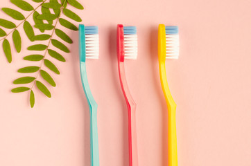 Colored toothbrushes composition on pink background. Flat lay.