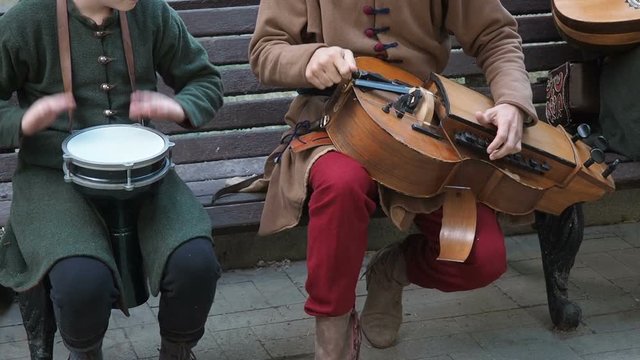Street musicians dressed in vintage ethnic oriental clothes play music on traditional Middle Eastern musical instruments turkish darbuka and hurdy-gurdy