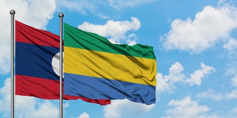 Laos and Gabon flag waving in the wind against white cloudy blue sky together. Diplomacy concept, international relations.