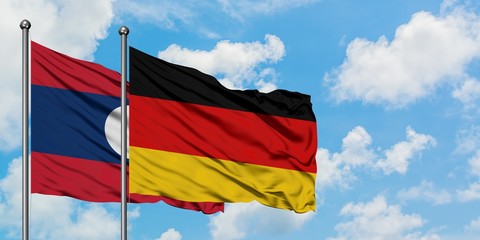 Laos and Germany flag waving in the wind against white cloudy blue sky together. Diplomacy concept, international relations.