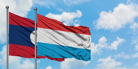 Laos and Luxembourg flag waving in the wind against white cloudy blue sky together. Diplomacy concept, international relations.