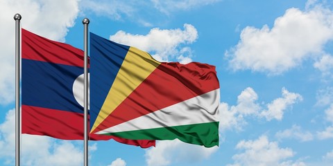 Laos and Seychelles flag waving in the wind against white cloudy blue sky together. Diplomacy...