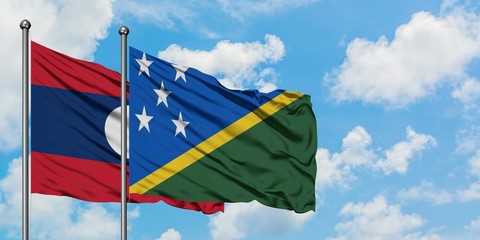 Laos and Solomon Islands flag waving in the wind against white cloudy blue sky together. Diplomacy concept, international relations.