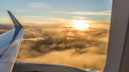 views from the window of an airplane above the clouds at sunset