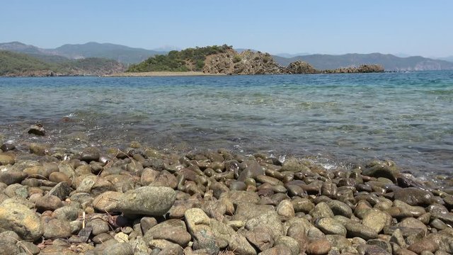 Flat island, Fethiye area, Turkey - 25th of July 2019: 4K Landswell and dark pebble on the uninhabited island
