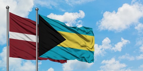 Latvia and Bahamas flag waving in the wind against white cloudy blue sky together. Diplomacy concept, international relations.