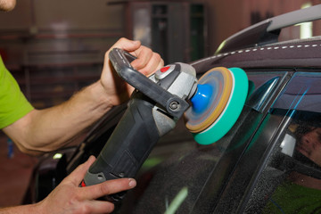 The master polishes plastic on a car with a grinder with paste.