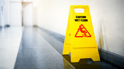 Sign showing warning of caution wet floor on wet tile floor
