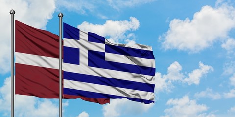 Latvia and Greece flag waving in the wind against white cloudy blue sky together. Diplomacy concept, international relations.