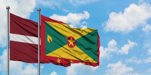 Latvia and Grenada flag waving in the wind against white cloudy blue sky together. Diplomacy concept, international relations.