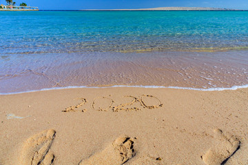 New year 2020. Inscription on a sandy beach. Tropical celebration concept
