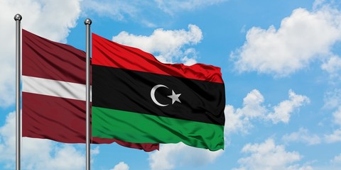 Latvia and Libya flag waving in the wind against white cloudy blue sky together. Diplomacy concept, international relations.