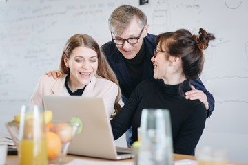 Authentic image of coworkers talking to boss over video call in the office. Colleagues  using laptop to discuss a project with their superior.