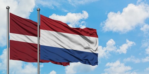 Latvia and Netherlands flag waving in the wind against white cloudy blue sky together. Diplomacy concept, international relations.