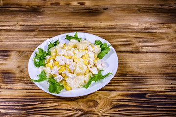 Festive salad with chicken breast, canned pineapple, cheese, sweet corn and mayonnaise on wooden table