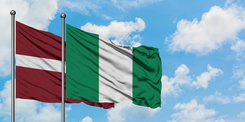 Latvia and Nigeria flag waving in the wind against white cloudy blue sky together. Diplomacy concept, international relations.