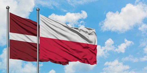 Latvia and Poland flag waving in the wind against white cloudy blue sky together. Diplomacy concept, international relations.