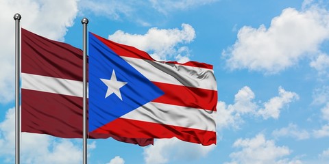 Latvia and Puerto Rico flag waving in the wind against white cloudy blue sky together. Diplomacy concept, international relations.