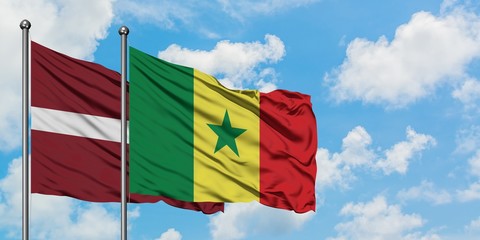 Latvia and Senegal flag waving in the wind against white cloudy blue sky together. Diplomacy concept, international relations.