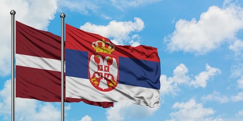 Latvia and Serbia flag waving in the wind against white cloudy blue sky together. Diplomacy concept, international relations.