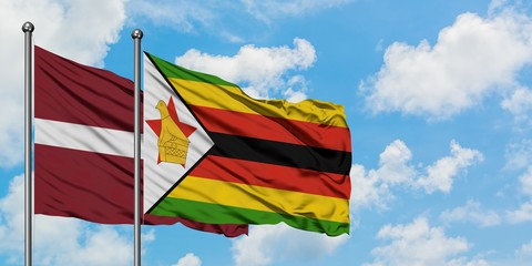 Latvia and Zimbabwe flag waving in the wind against white cloudy blue sky together. Diplomacy concept, international relations.
