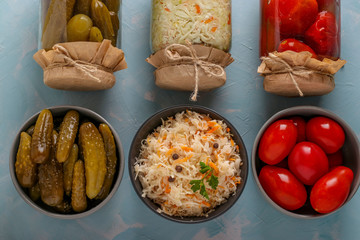 Homemade Sauerkraut, salted tomatoes and cucumbers in a bowls and a glass jars on a light blue background, Concept Fermented Vegetables,Top view