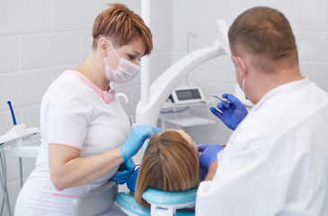 Fototapeta na wymiar Doctor dentist treats teeth of a beautiful young girl patient. The girl on reception at the dentist. Doctor dentist treats tooth