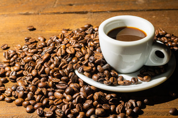 Coffee beans with cup on wooden background