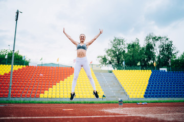 Fototapeta na wymiar Optimistic lady in sportswear jumping and smiling