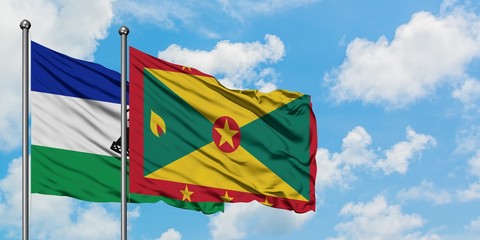 Lesotho and Grenada flag waving in the wind against white cloudy blue sky together. Diplomacy concept, international relations.