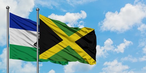 Lesotho and Jamaica flag waving in the wind against white cloudy blue sky together. Diplomacy concept, international relations.