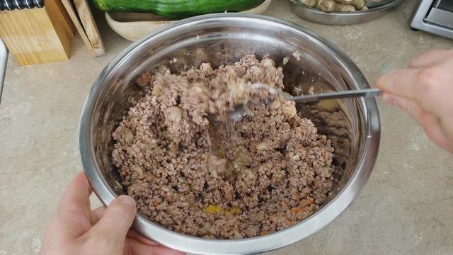 Home cooking - Mixing whole chicken eggs with previously cooked and ground and seasoned beef making stuffing for croquet or wraps with meat filling.