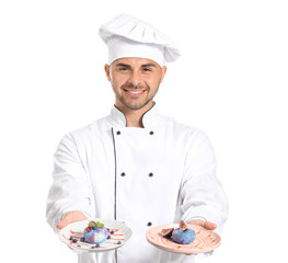 Male confectioner with tasty desserts on white background