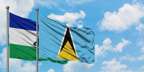 Lesotho and Saint Lucia flag waving in the wind against white cloudy blue sky together. Diplomacy...