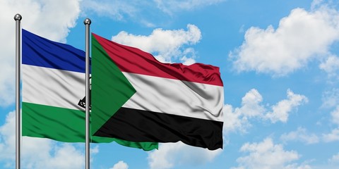 Lesotho and Sudan flag waving in the wind against white cloudy blue sky together. Diplomacy concept, international relations.