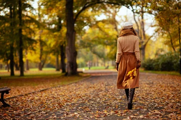 Foto op Canvas young woman with yellow leaves walking outside in autumn park © Alliance