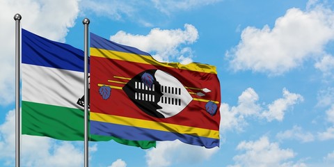 Lesotho and Swaziland flag waving in the wind against white cloudy blue sky together. Diplomacy...