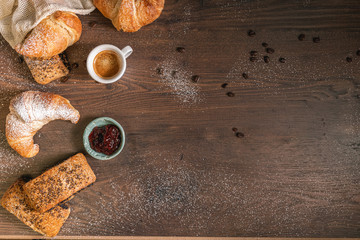Wooden table with coffee bean and sugar powder in the middle and pastries and coffee on the side