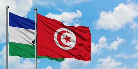 Lesotho and Tunisia flag waving in the wind against white cloudy blue sky together. Diplomacy concept, international relations.