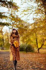 woman with yellow leaves walking outdoors in autumn park