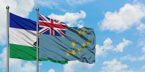 Lesotho and Tuvalu flag waving in the wind against white cloudy blue sky together. Diplomacy...