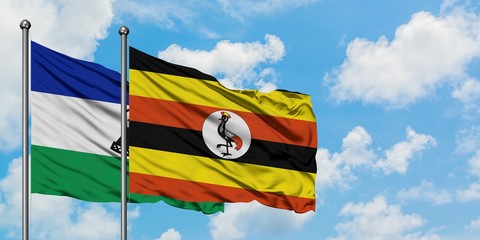 Lesotho and Uganda flag waving in the wind against white cloudy blue sky together. Diplomacy concept, international relations.