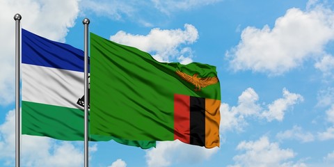 Lesotho and Zambia flag waving in the wind against white cloudy blue sky together. Diplomacy...
