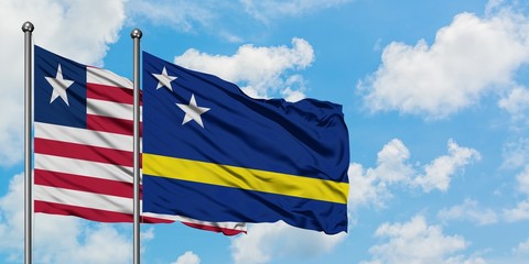 Liberia and Curacao flag waving in the wind against white cloudy blue sky together. Diplomacy concept, international relations.