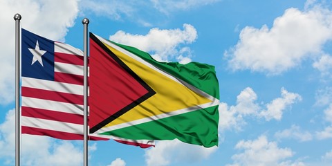Liberia and Guyana flag waving in the wind against white cloudy blue sky together. Diplomacy concept, international relations.