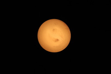 Closeup at light bulb that looks like an orange yellow planet with atmosphere and hurricanes at its surface isolated on black background