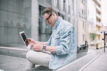 Cool young man using laptop on street