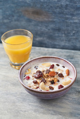 Bowl of granola with milk, nuts, raisins and cranberries. Concept for a tasty and healthy meal. Rustic wooden background. Close up.