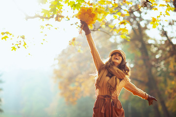 happy woman with yellow leaves rejoicing outside in autumn park