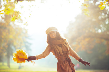 cheerful woman with yellow leaves outside in autumn park